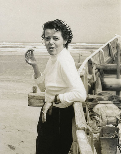 Potrait of Charlotte at the beach leaning on the side of a boat with a snack in hand